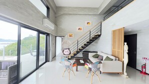 A modern living room with a large window, a staircase, and a sofa. - Ocean view retreat! Luxury villa with sauna (本部町)