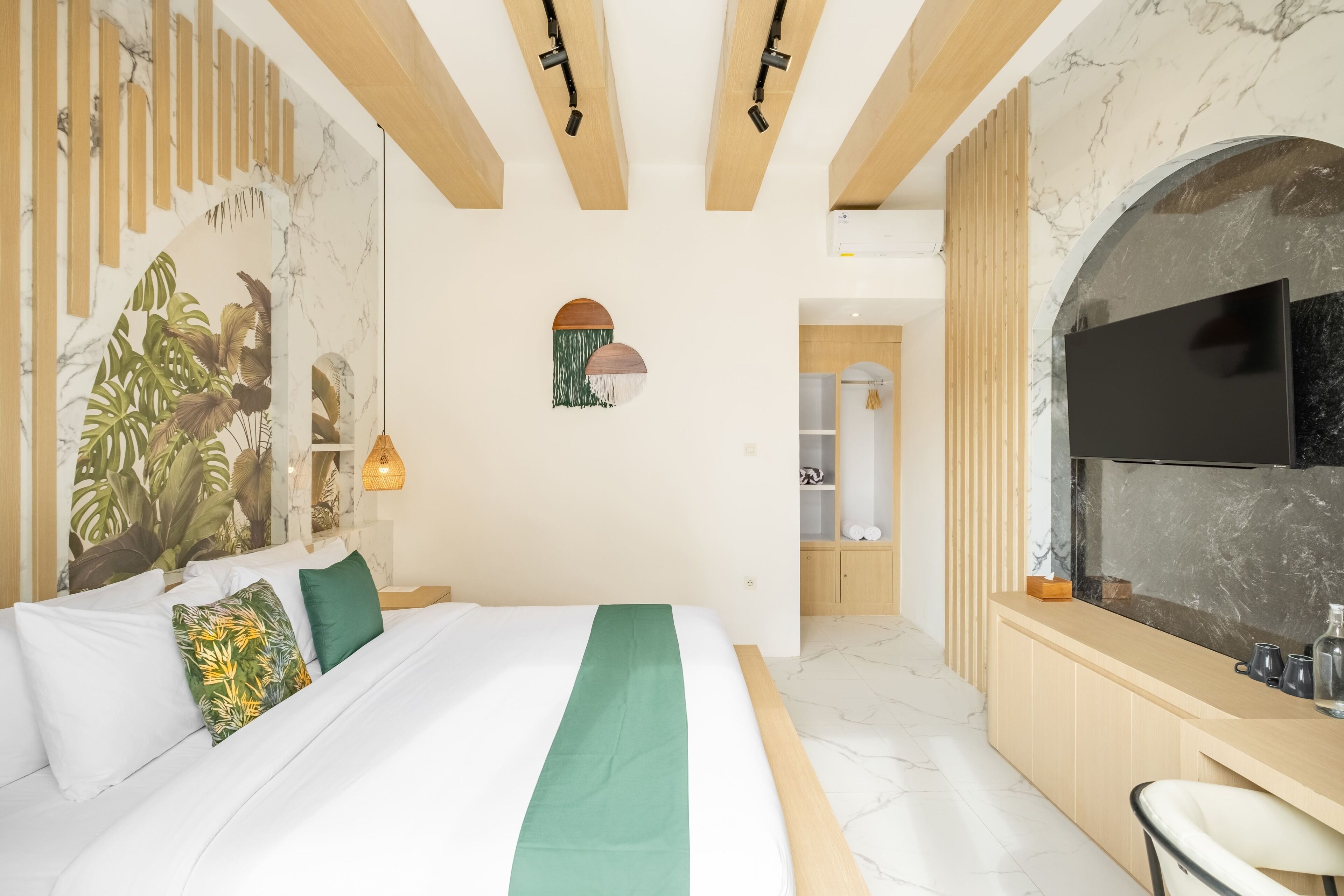 Una habitación de hotel moderna con una cama grande, un televisor y una zona de cocina.