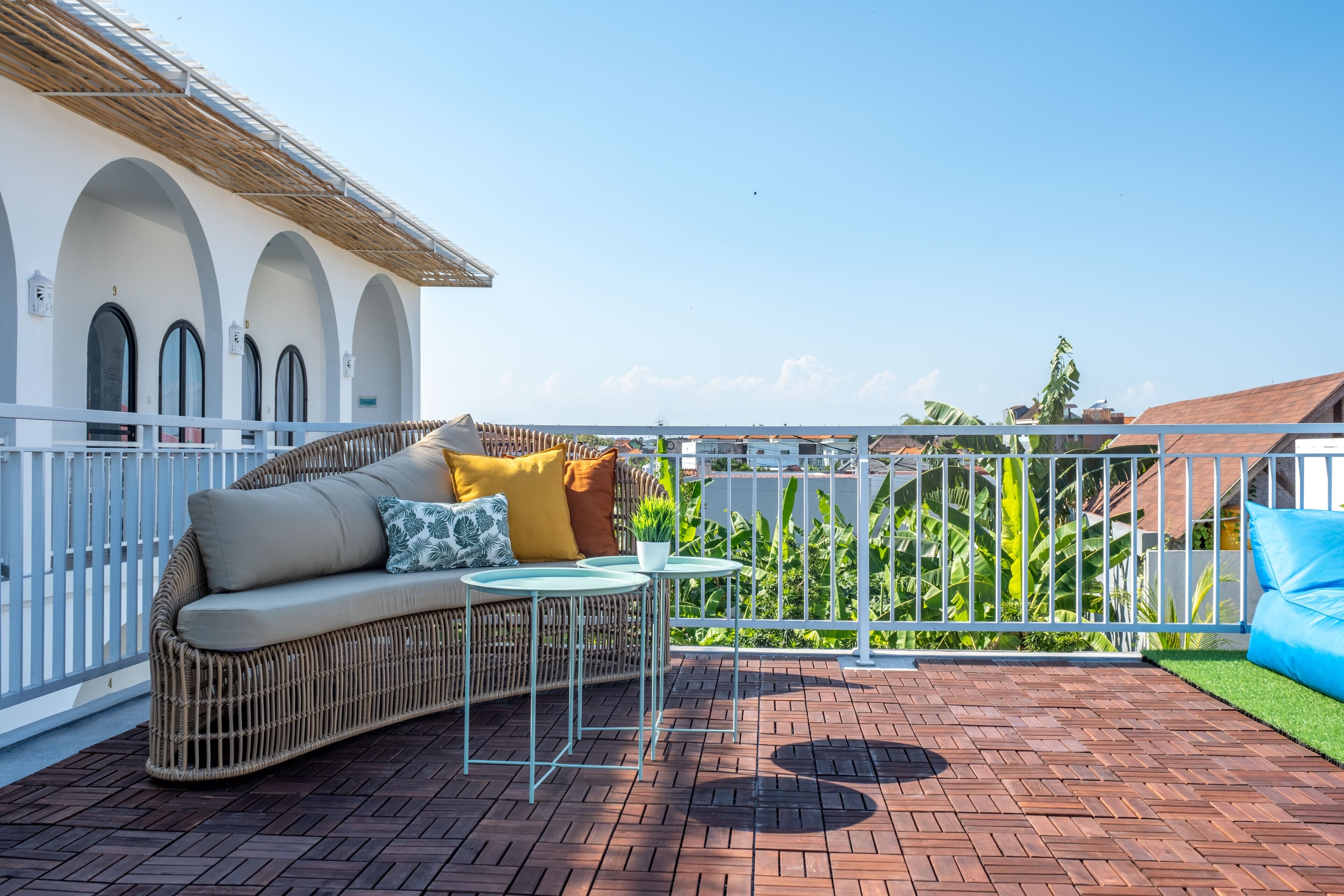 A balcony with a wicker sofa, a small table, and a blue cushion.
