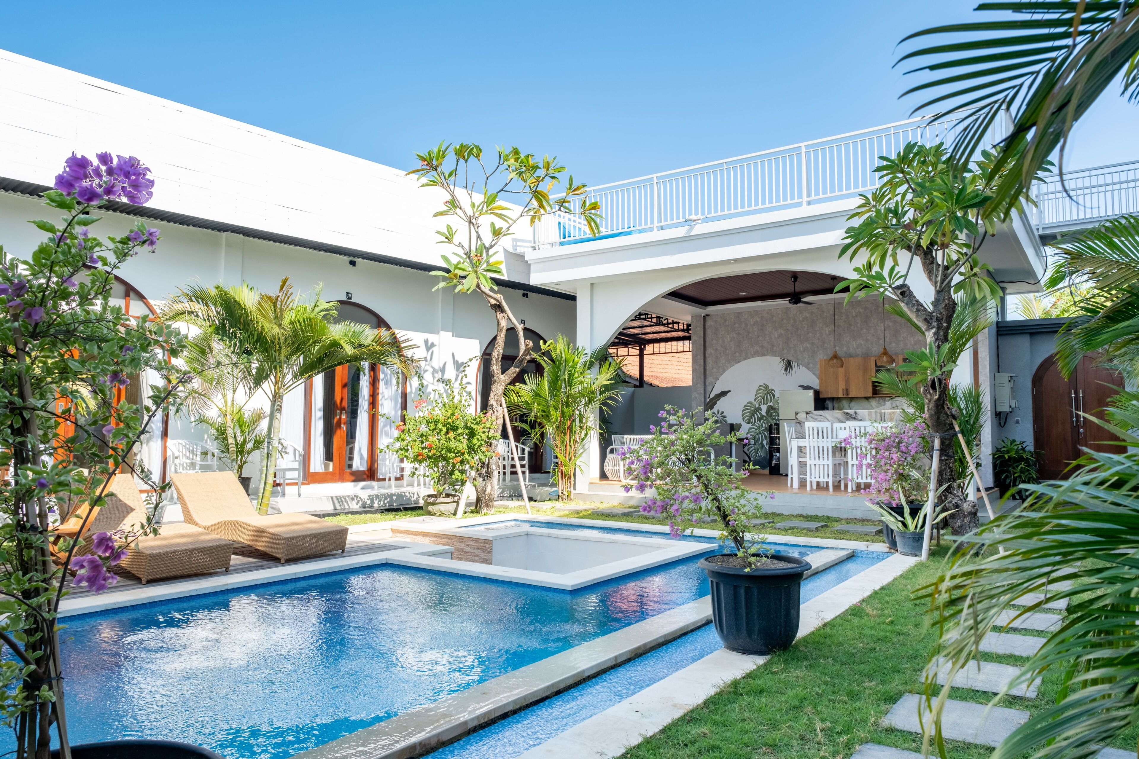 A swimming pool with lounge chairs, a covered patio area, and potted plants.