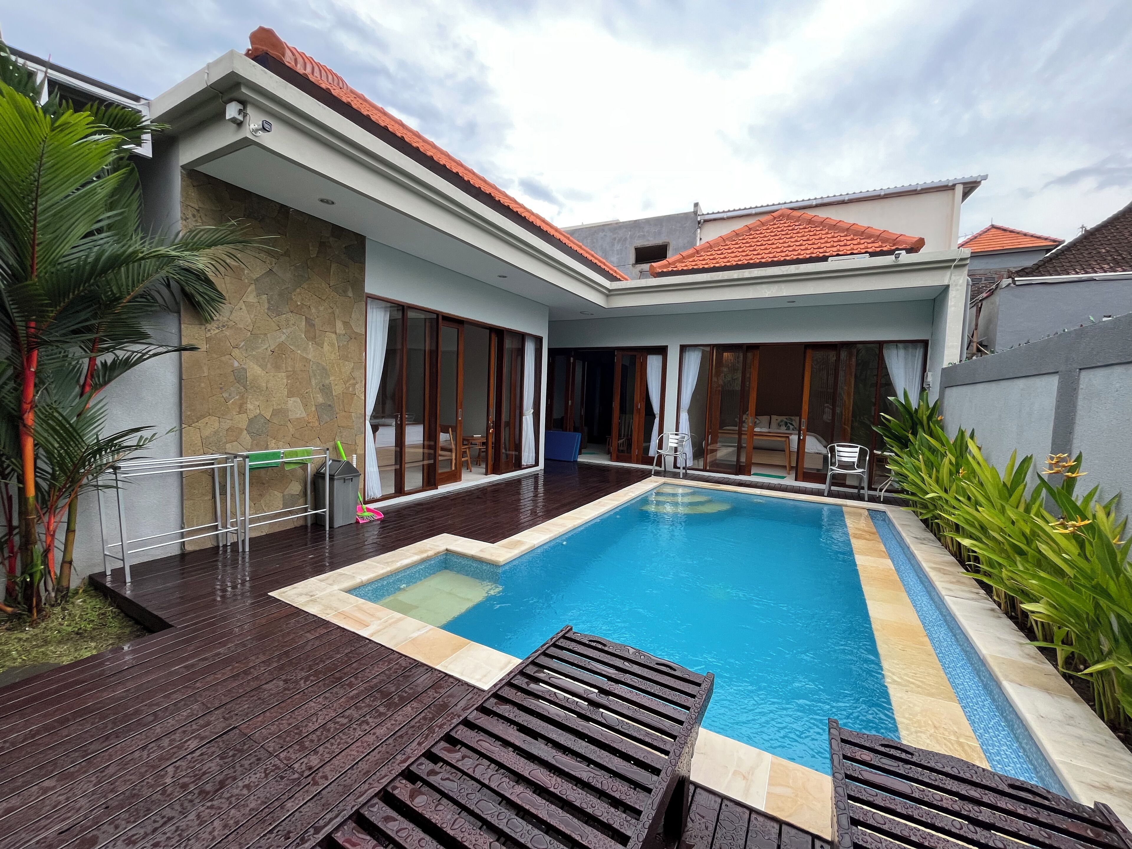 A modern house with a swimming pool, large sliding glass doors, and a stone exterior wall.