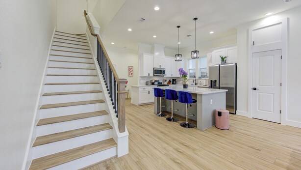 A modern kitchen with a central island, wooden staircase, and pendant lighting. - Prime EADO 4 BR Downtown Houston  (Houston)