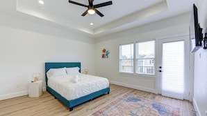 A bedroom with a bed, a ceiling fan, a window, and a door. - Prime EADO 4 BR Downtown Houston  (Houston)
