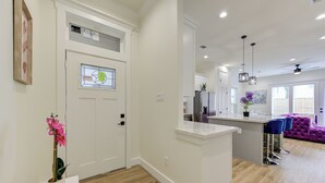 A modern kitchen with white cabinets, a central island, and a purple sofa in the living area. - Prime EADO 4 BR Downtown Houston  (Houston)