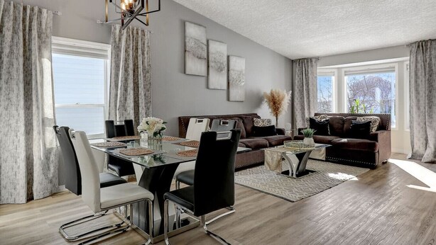 En moderne stue med spiseområde, store vinduer og udsigt til det fri.