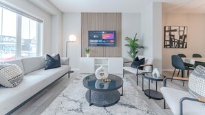 En moderne stue med sofa, sofabord og fjernsyn ophængt på væggen.