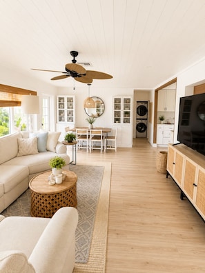 En moderne stue med sofa, sofabord, spisebord og fjernsyn.