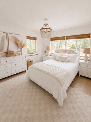 Une chambre à coucher avec un grand lit, des tables de chevet, une commode, un lustre et de grandes fenêtres.