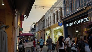 Una escena callejera con peatones, una cafetería llamada 'Rush Coffee' y un carrito de comida.