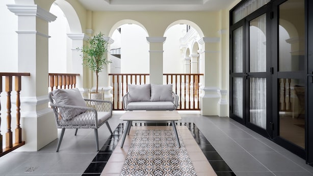 Un balcón amplio con sofá, sillas y un tapete estampado.