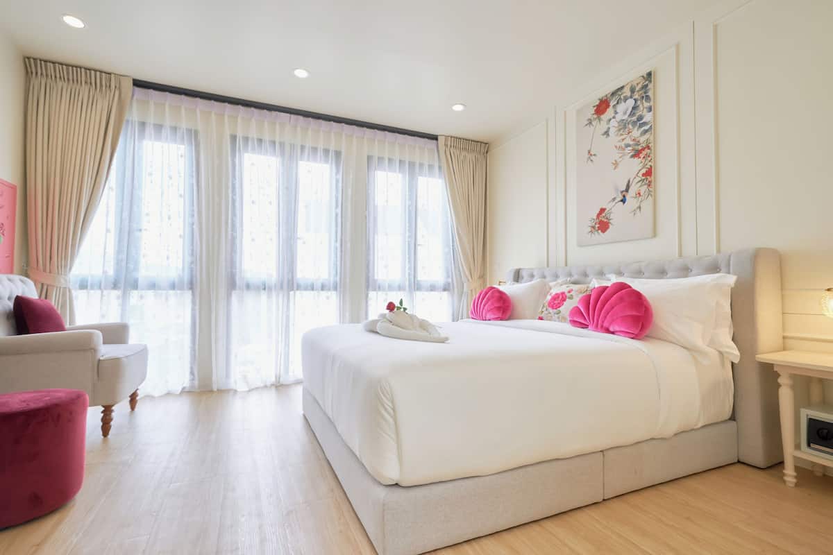 Un dormitorio amplio con una cama grande, una silla y una mesita de noche.