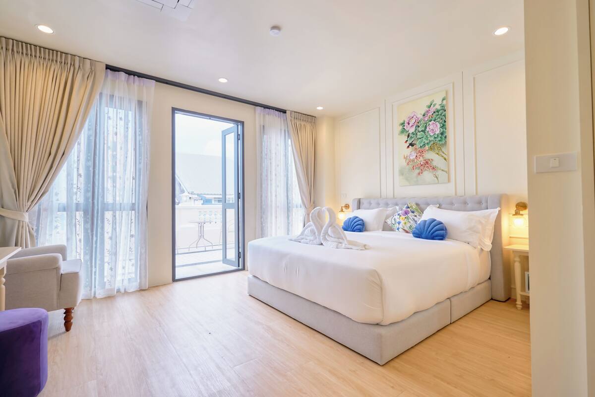 Habitación de hotel moderna con una cama grande, una silla, una mesa y vistas al exterior.