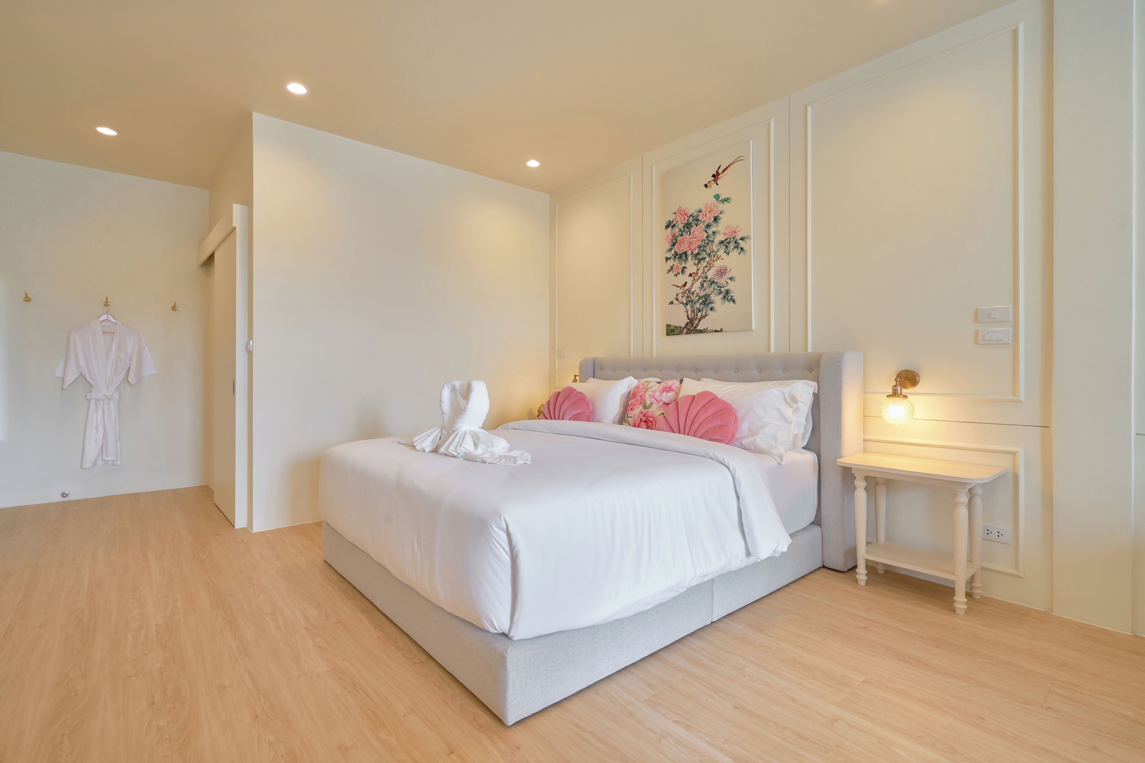 A neatly arranged bedroom with a large bed, a bedside table, and a wall-mounted light fixture.