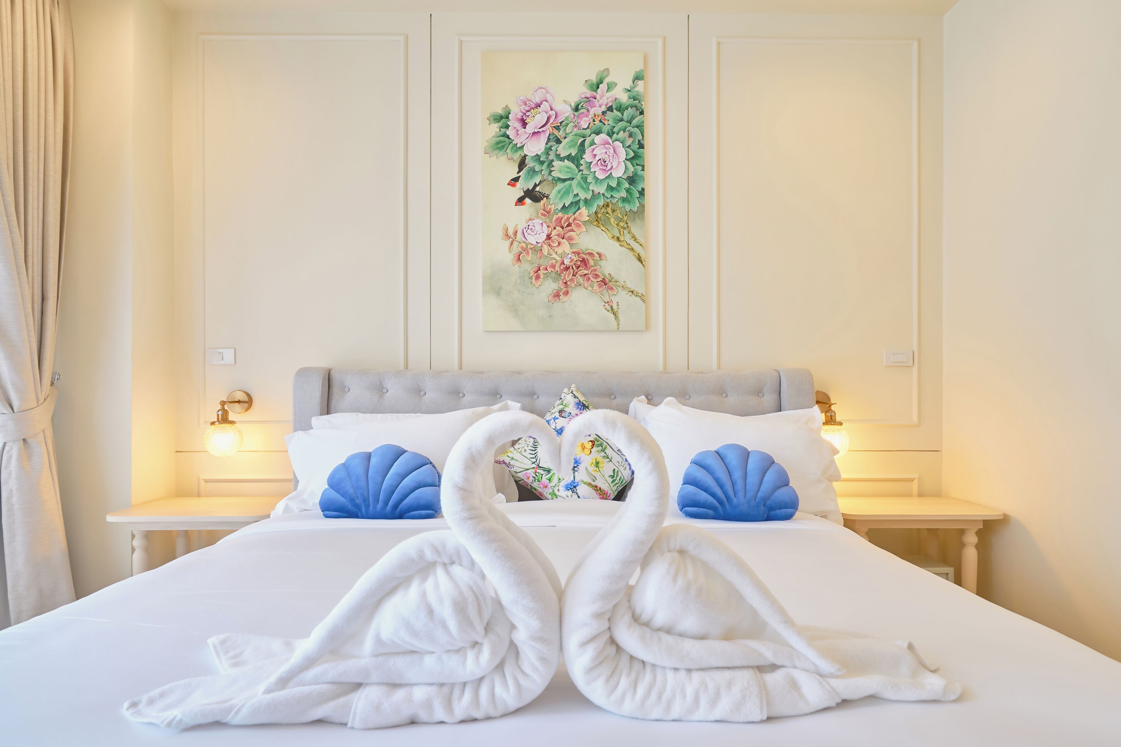 Una habitación de hotel con una cama grande, dos mesitas de noche, un cuadro en la pared y una ventana con cortinas.