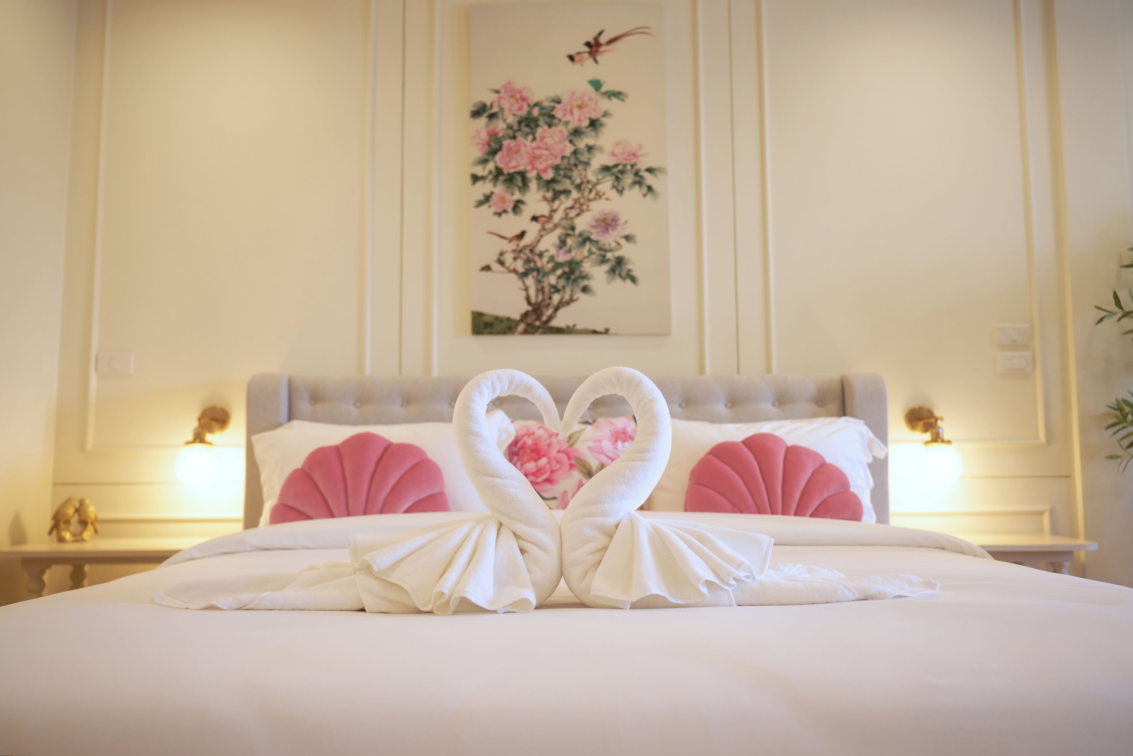 A neatly made bed with a heart-shaped towel arrangement in the center.
