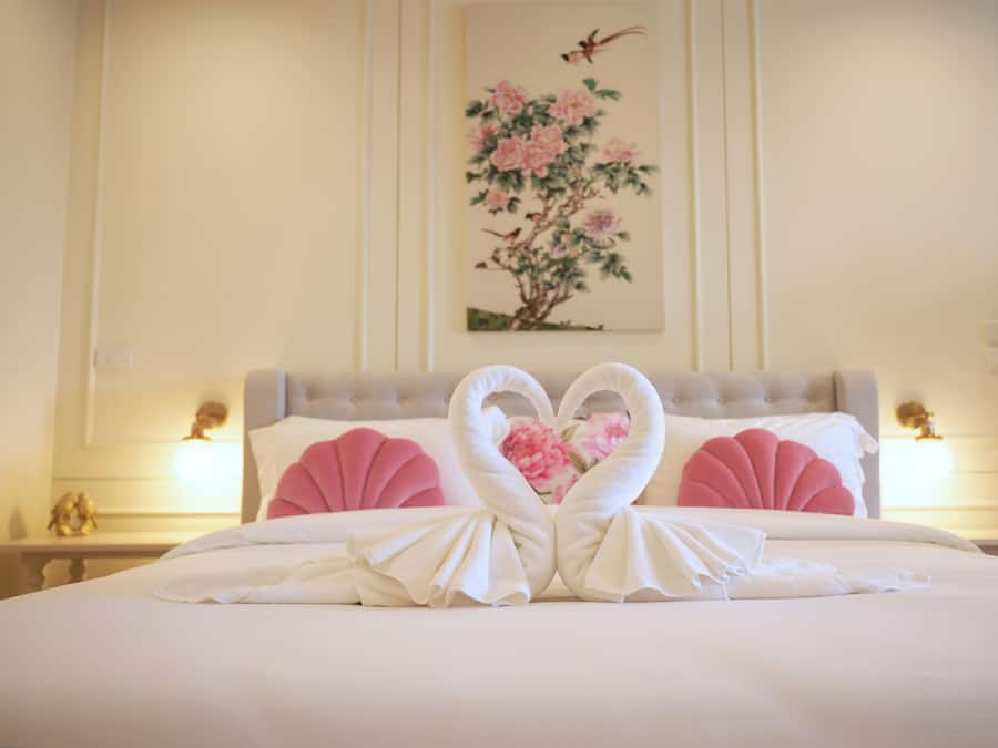 Una cama bien hecha con un arreglo de toallas con forma de corazón en el centro.