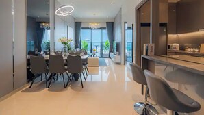 A modern dining area with a long table, chairs, and a chandelier. - Kotrip MarQ Paradise Vacation (Ho Chi Minh City)
