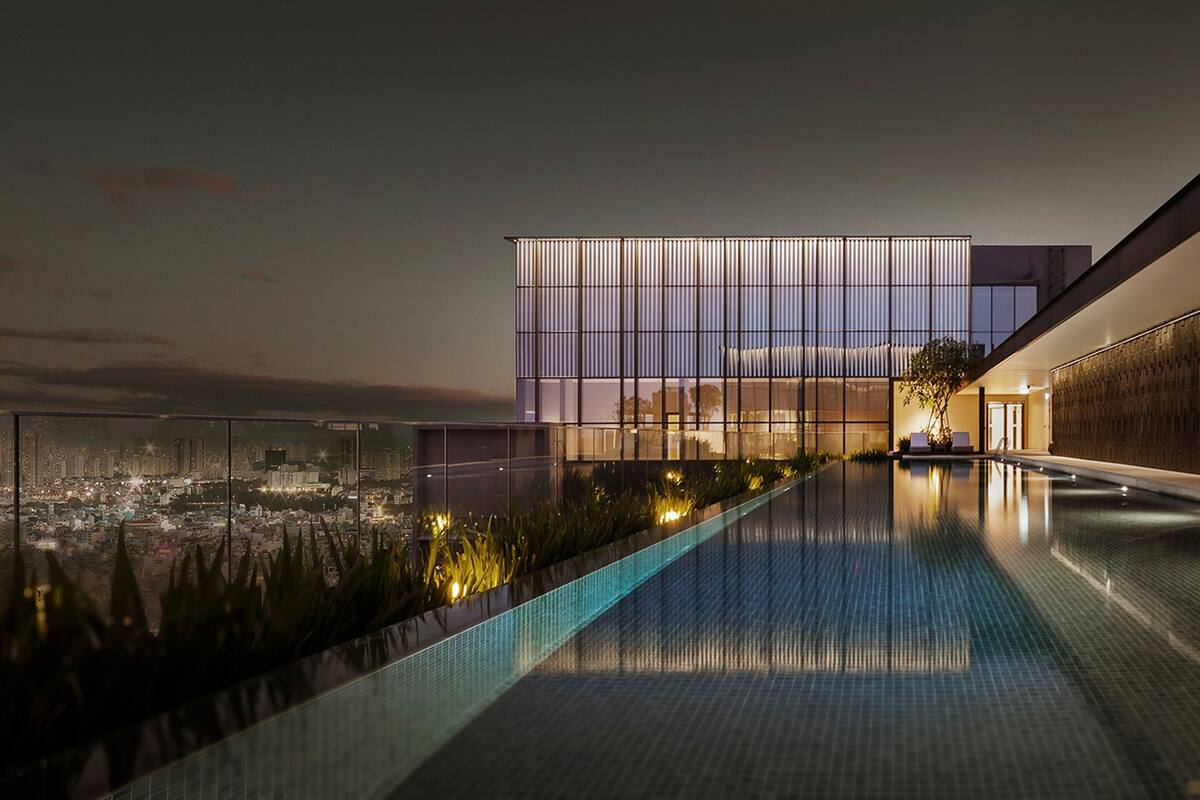 A modern building with a reflective pool and a city view at dusk.