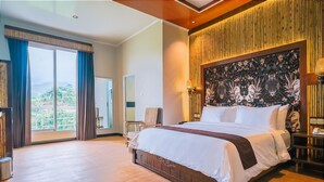 A spacious bedroom with a large bed, a view of the outdoors, and a decorative headboard. - Horison Resort Dieng (Kejajar)