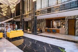 Eine moderne Lobby mit Marmorboden, einer Rezeption und einer Treppe.
