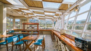 A spacious restaurant with high ceilings, large windows, and a view of the mountains. - Horison Resort Dieng (Kejajar)