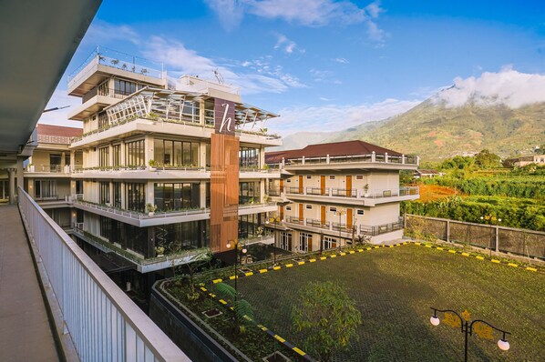Ein mehrstöckiges Hotel mit Balkonen, einem Innenhof und einer Bergkulisse.