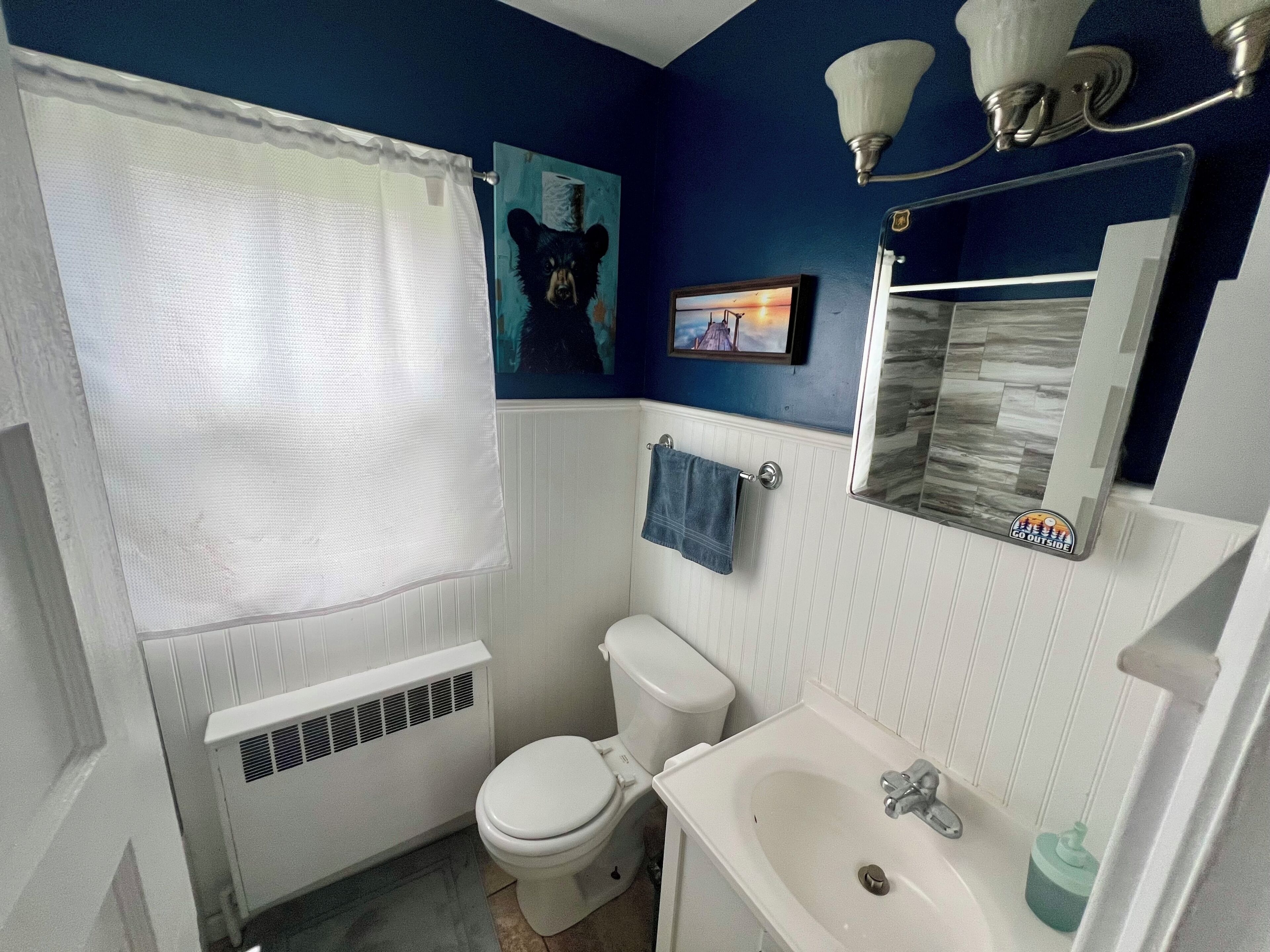 Un baño con inodoro blanco, lavamanos, espejo y cortina de ducha.