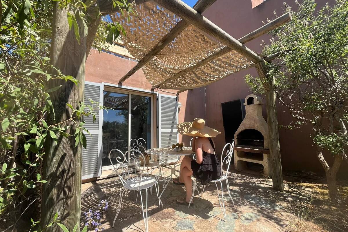 Een terras met tuinmeubilair, een pergola en een stenen buitenoven.