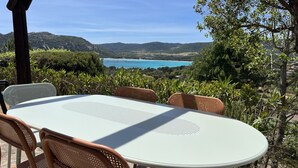 Un espace de restauration en plein air, avec une table et des chaises, offrant une vue sur un paysage pittoresque composé de collines et d’une étendue d’eau.