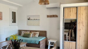 Une pièce comprenant une table à manger en bois, un canapé recouvert d’un tissu vert, un luminaire suspendu en fibres tressées et un meuble en bois.