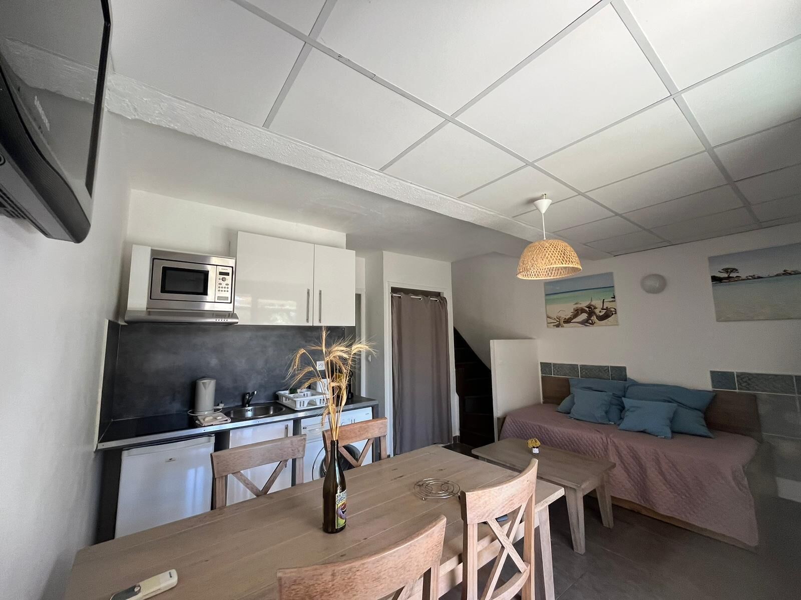 Ett kompakt bostadsutrymme med ett litet kök, en matplats och en säng.