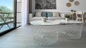 Ein modernes Wohnzimmer mit einer Couch, zwei weißen Couchtischen und einem Essbereich mit Stühlen.