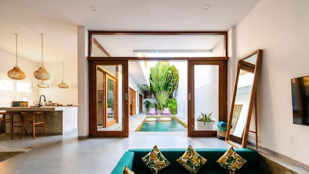 Un interior moderno con cocina, zona de comedor y una piscina central.