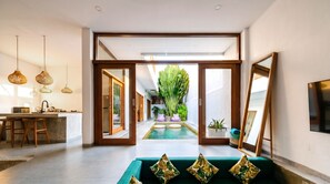 A modern interior with a kitchen, dining area, and a central pool area. - Villa Kulibul by GORO (Canggu)