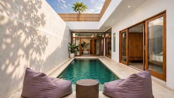 Una piscina al aire libre, sombrillas, sillones reclinables de piscina