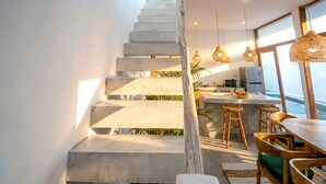 Una cocina moderna con una isla integrada, taburetes de madera y lámparas colgantes.
