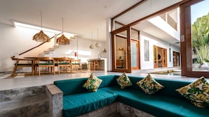 Un interior moderno con un sofá color turquesa, una mesa de comedor de madera y lámparas colgantes.