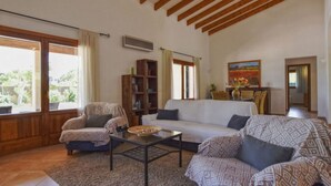 A living room with a sofa, armchairs, a coffee table, and a bookshelf.