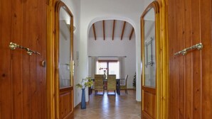 A hallway with wooden doors leading to a dining area with a table and chairs.
