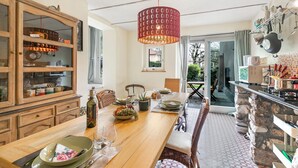 A dining area with a wooden table set for four, a hanging red pendant light, and a view of the outdoors through a glass door. - La Maison Du Lac - 50 Meters From Lake , Private Parking&bbq (Monvalle)