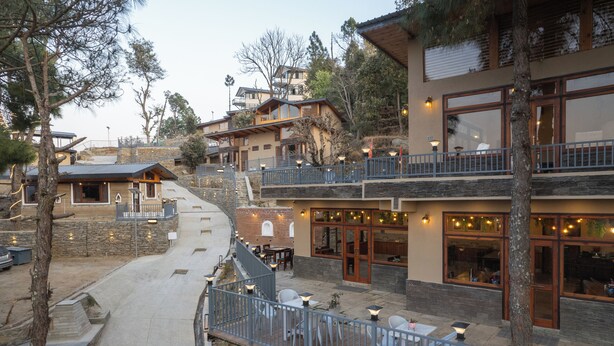 Un restaurante con terraza, escalones de piedra y vistas a edificios circundantes.