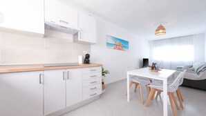 A modern kitchen with white cabinets, a wooden countertop, and a dining area with a white table and chairs.