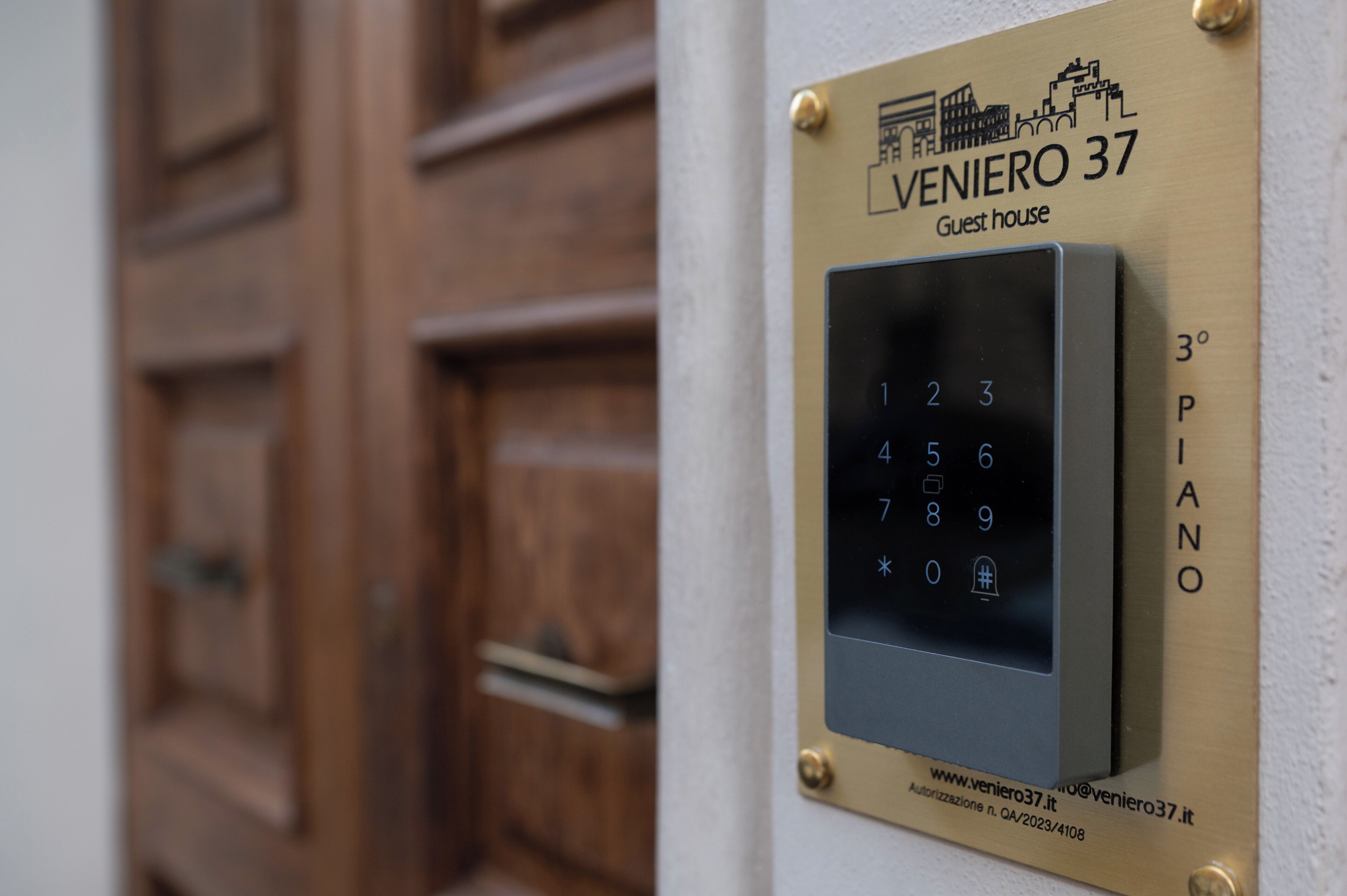 Una cerradura electrónica con teclado numérico y una placa encima que dice "VENIERO 37 Guest house" y "3° PIANO".