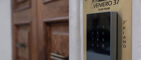 Una cerradura electrónica con teclado numérico y una placa encima que dice "VENIERO 37 Guest house" y "3° PIANO".