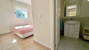A bedroom with a bed, a bathroom with a sink and mirror, and a door leading to another room. - Beautiful and comfortable apartment  with communal pool in Denia, Costa Blanca, Spain for 6 persons (Denia)