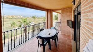 A balcony with a table and chairs, a TV mounted on the wall, and a view of the countryside. - Beautiful and comfortable apartment in Denia, Costa Blanca, Spain  with communal pool for 4 persons (Denia)