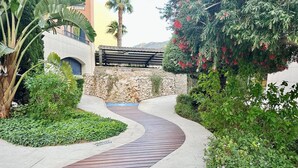 A curved pathway leading to a building with a stone wall and a wooden pergola. - Beautiful and comfortable apartment in Denia, Costa Blanca, Spain  with communal pool for 4 persons (Denia)