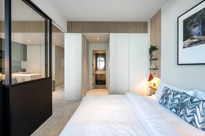 A modern hotel room with a large bed, a desk, and a view of the hallway. - Modern 1BR w/ Balcony in Business Bay (Dubai)