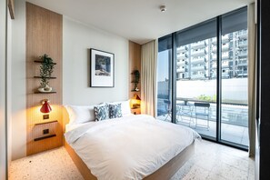 Ein modernes Hotelzimmer mit einem großen Bett, Blick auf die Stadt und einer Wandablage mit Pflanzen.
