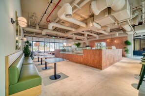 A modern interior with a central counter, green seating, and large windows.